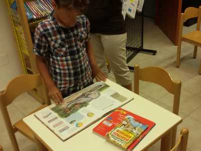 Un bambino mentre maneggia un libro dedicato ai dinosauri